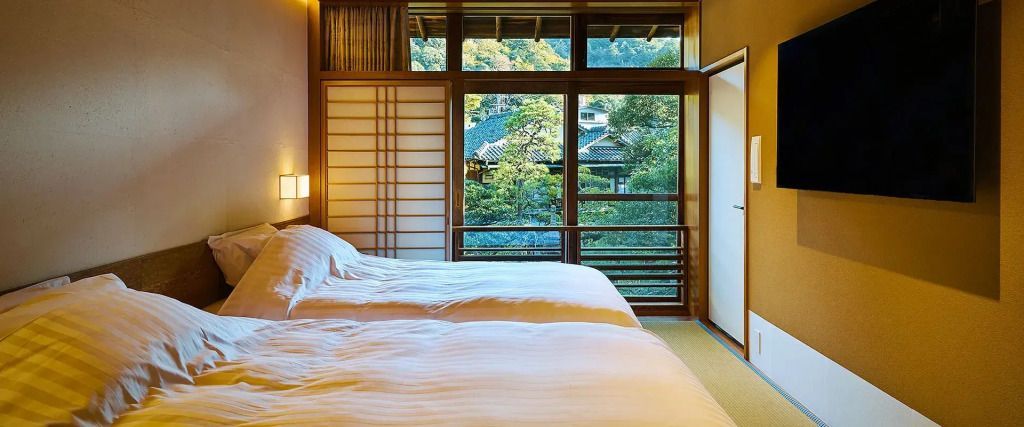 Zwei Betten im japanischen Stil mit Aussicht auf einen Garten durch große Fenster