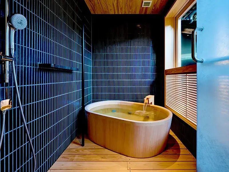Modernes Badezimmer mit Holzbadewanne und blauer Fliesenwand