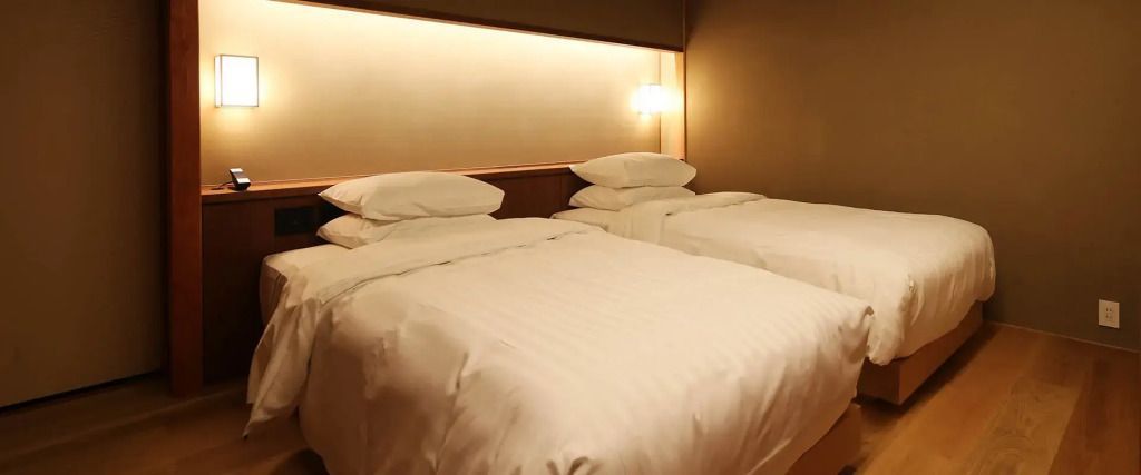 Gemütliches Zimmer mit zwei großen Betten und stilvoller Beleuchtung