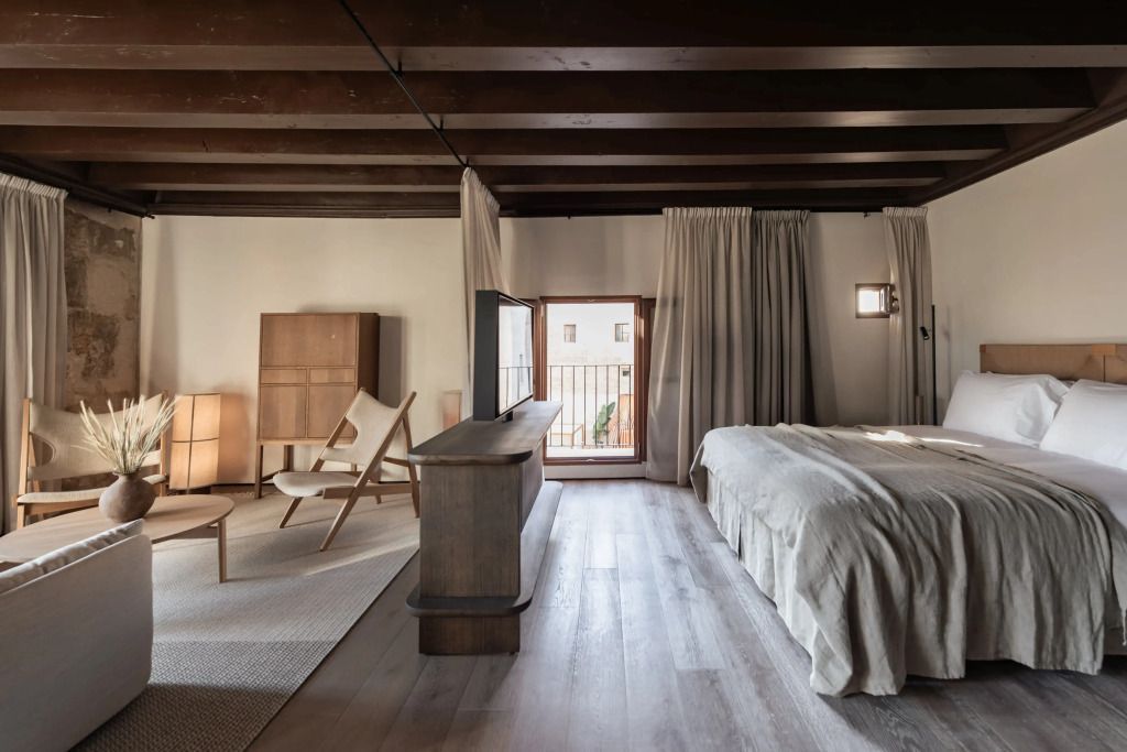 Elegante Suite mit Holzbalkendecke. Gemütlicher Sitzbereich und großes Bett.