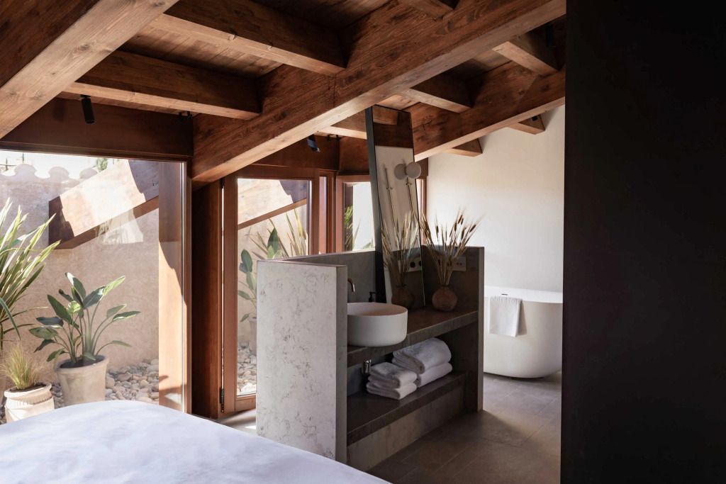Modernes Badezimmer in der Suite mit Holzbalken. Freistehende Badewanne und elegantes Waschbecken.