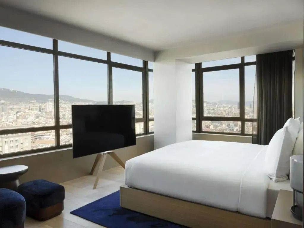 Geräumiges Schlafzimmer mit großen Fenstern und Blick auf die Stadt