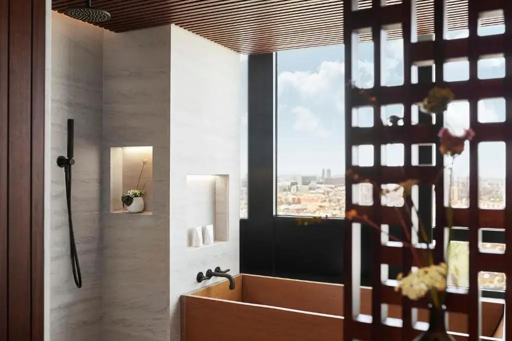 Luxuriöses Badezimmer mit freistehender Holzbadewanne und Stadtblick
