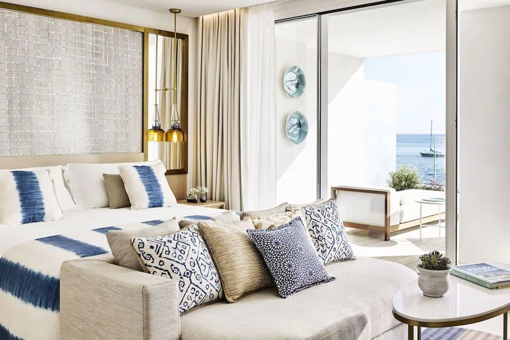 Helle Junior-Suite mit Doppelbett, Sofa und weitem Meerblick vom Balkon.