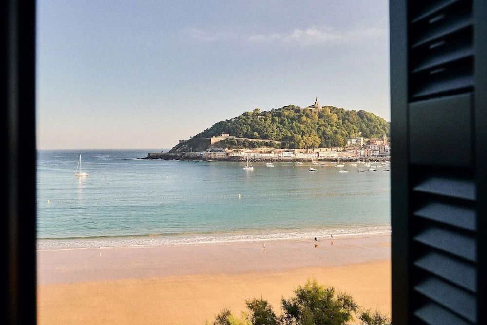 Aussicht vom Balkon auf Strand und grünen Hügel am Meer in San Sebastián