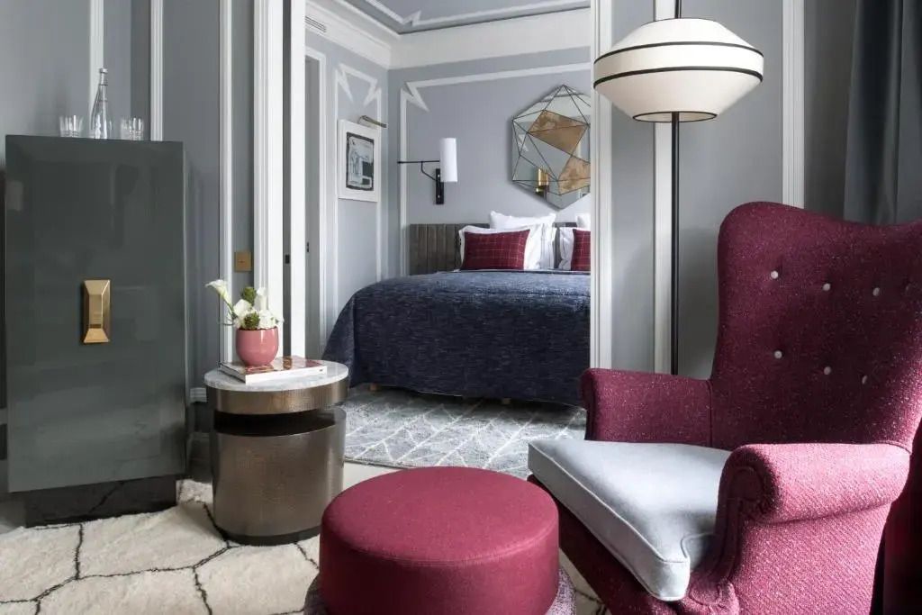 Stilvolle Suite mit rotem Sessel und Sicht auf Schlafzimmer im eleganten Design.