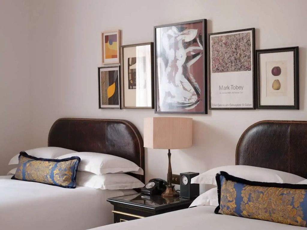 Zwei Einzelbetten mit eleganten Bezügen und künstlerischen Wandelementen im NoMad London.