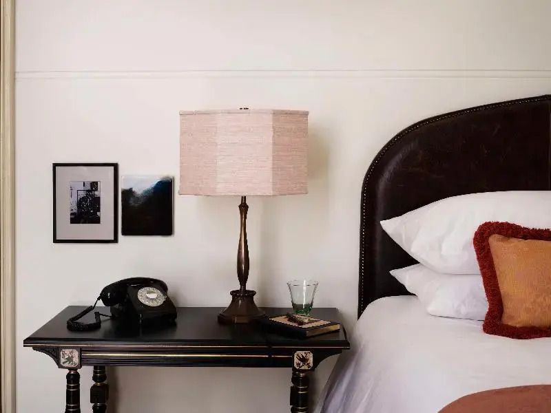 Nachttisch mit Vintage-Telefon und Lampe neben einem gemütlichen Bett