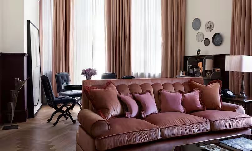 Große Suite mit stilvollem Sofa und weichen Kissen vor hohen Vorhängen