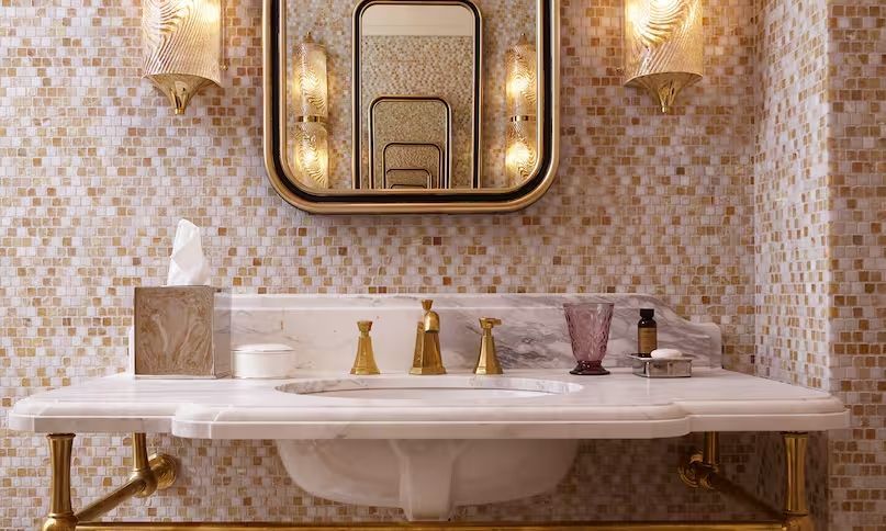 Elegantes Badezimmer mit Mosaikfliesen und goldenen Armaturen