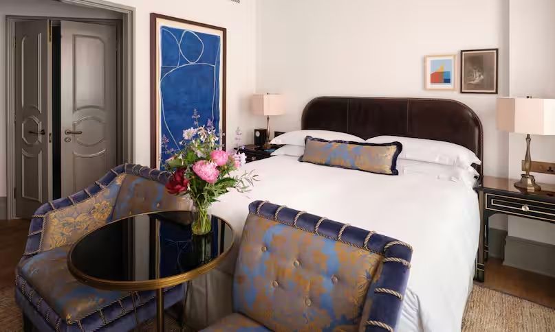 Elegantes Doppelzimmer mit kunstvoller Wanddekoration und frischen Blumen.