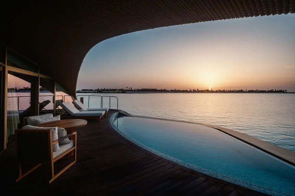 Sonnenuntergang am Wasser mit moderner Terrasse und komfortablen Liegen.