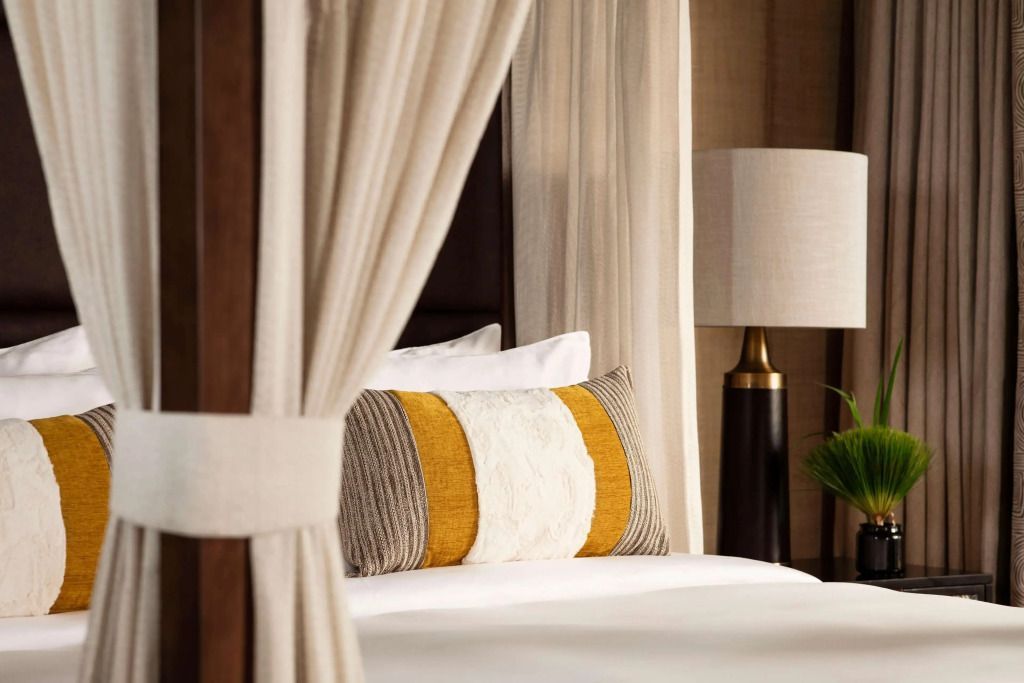 Bett mit Vorhängen und eleganten Kissen in neutralen Farben