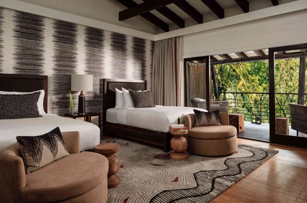 Elegantes Zimmer mit zwei Einzelbetten und Ausblick auf den Balkon mit Naturkulisse.