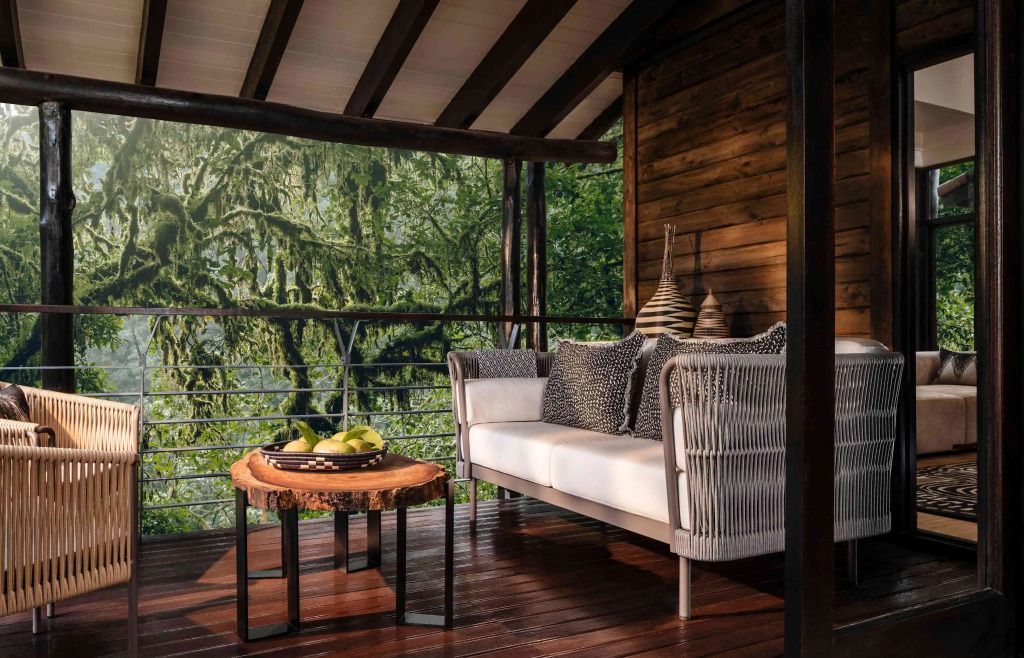 Balkon mit gemütlicher Sitzgelegenheit und Blick auf den grünen Regenwald.