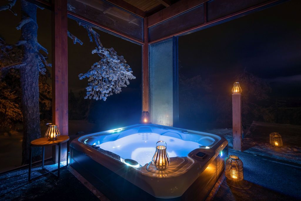 Beleuchteter Hot Tub auf der Terrasse der Octola Villa bei Nacht, umgeben von Laternen und Schnee