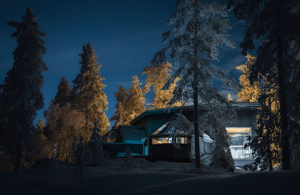 Glass Igloo Suite mit beleuchteten Glaswänden zwischen Kiefern in einer Herbstnacht