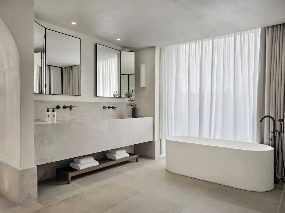 Modernes Badezimmer mit freistehender Badewanne und großen Spiegeln