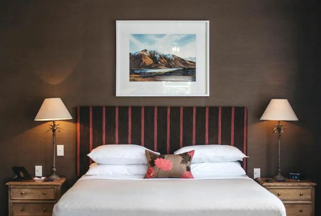 Gemütliches Schlafzimmer mit Doppelbett und Landschaftsgemälde an der Wand