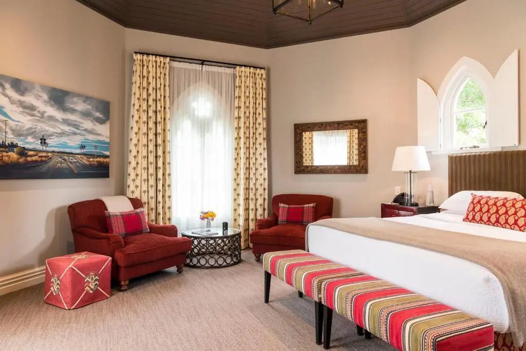 Suite mit Sitzbereich. Zwei Sessel und ein Bett mit gestreiften Details