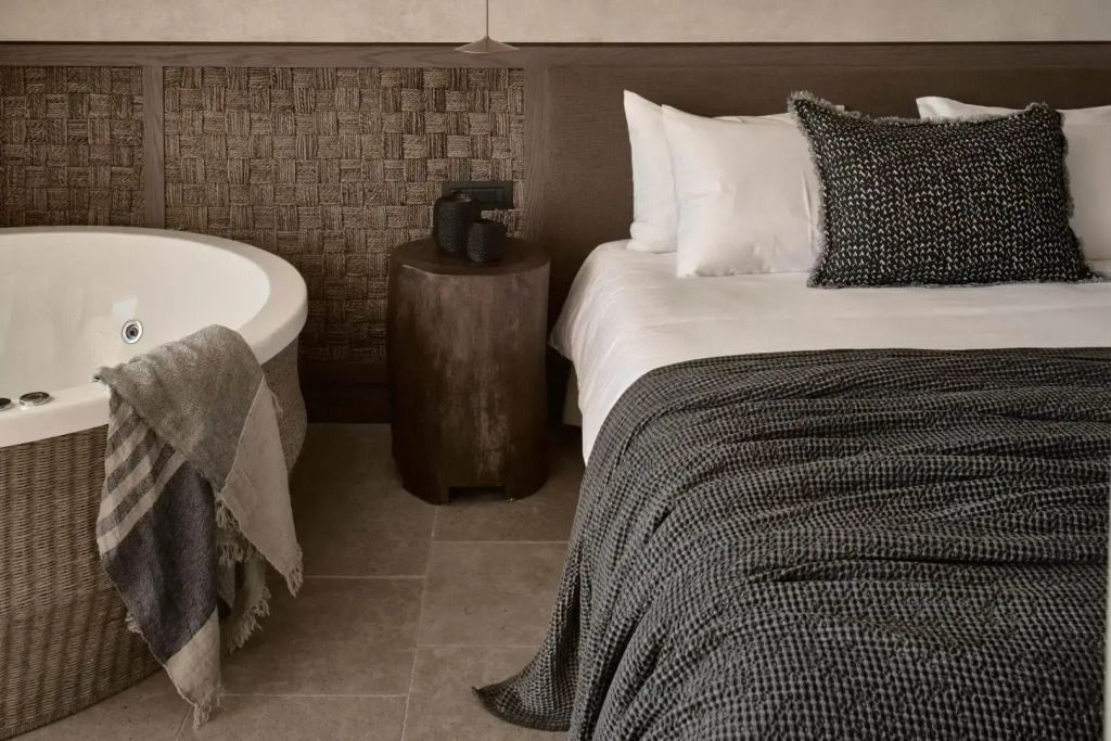 Hochwertig eingerichtetes Schlafzimmer mit elegantem Doppelbett und freistehender Badewanne
