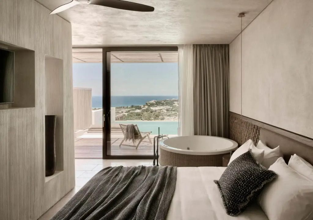 Suite mit Blick auf das Meer durch große Fensterfront Pool und Liegestuhl auf der Terrasse
