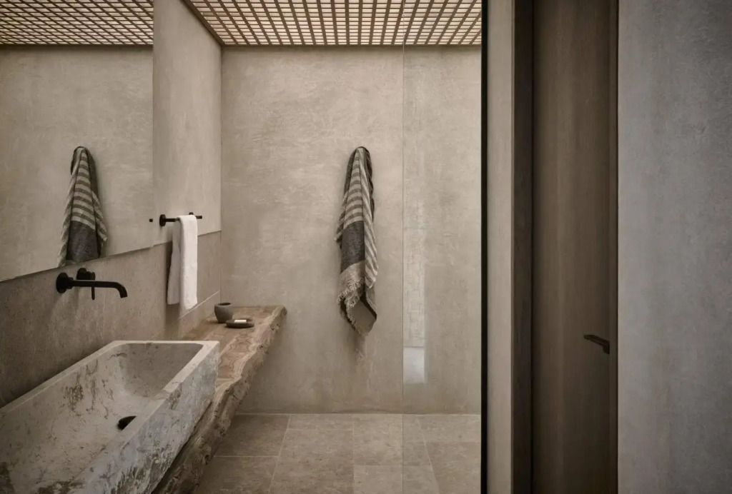 Minimalistisch gestaltetes Badezimmer mit großen Steinelementen und hängendem Handtuch