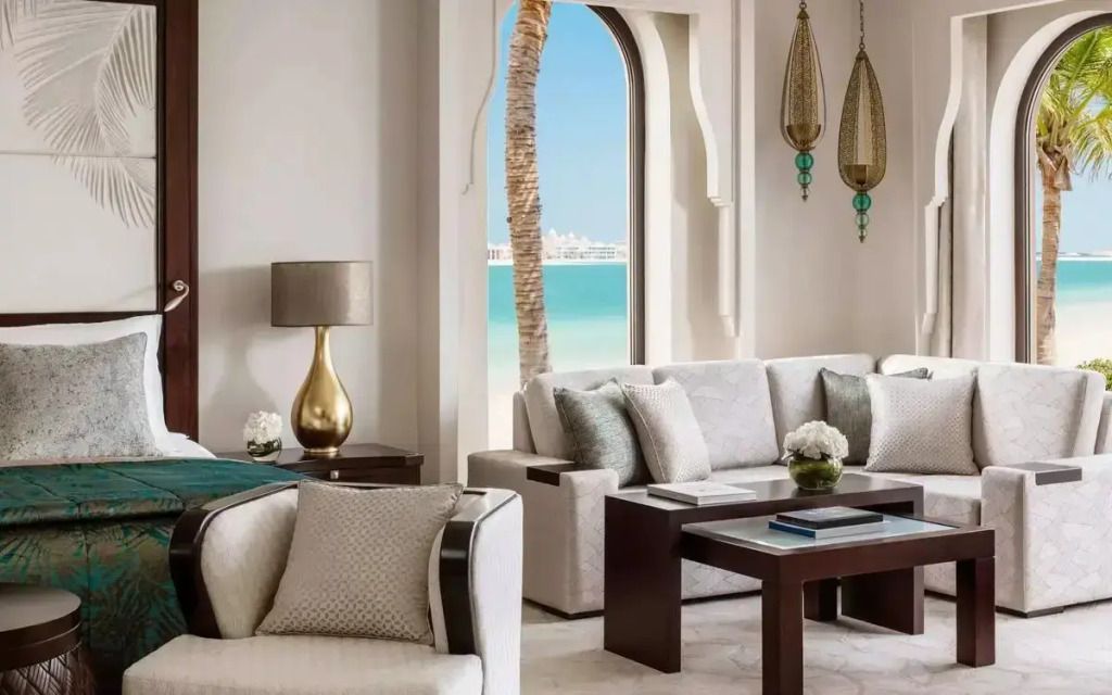 Elegante Wohnzimmeransicht mit Sofa und Meerblick durch ein großes Fenster mit Palmen.