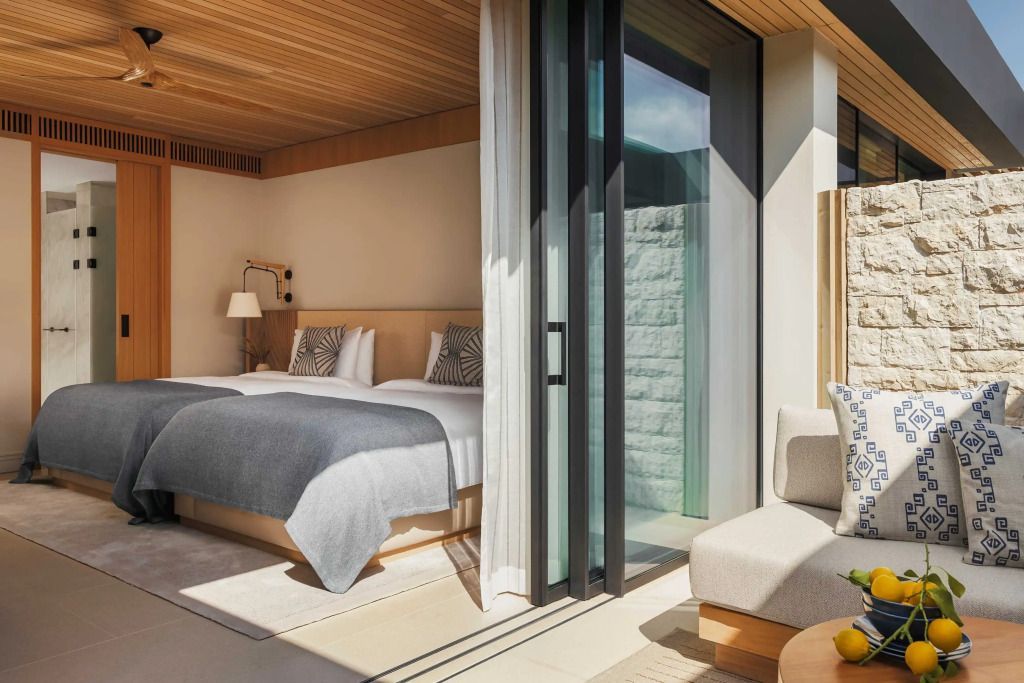 Elegantes Schlafzimmer mit Doppelbett und bodentiefen Fenstern in moderner Suite