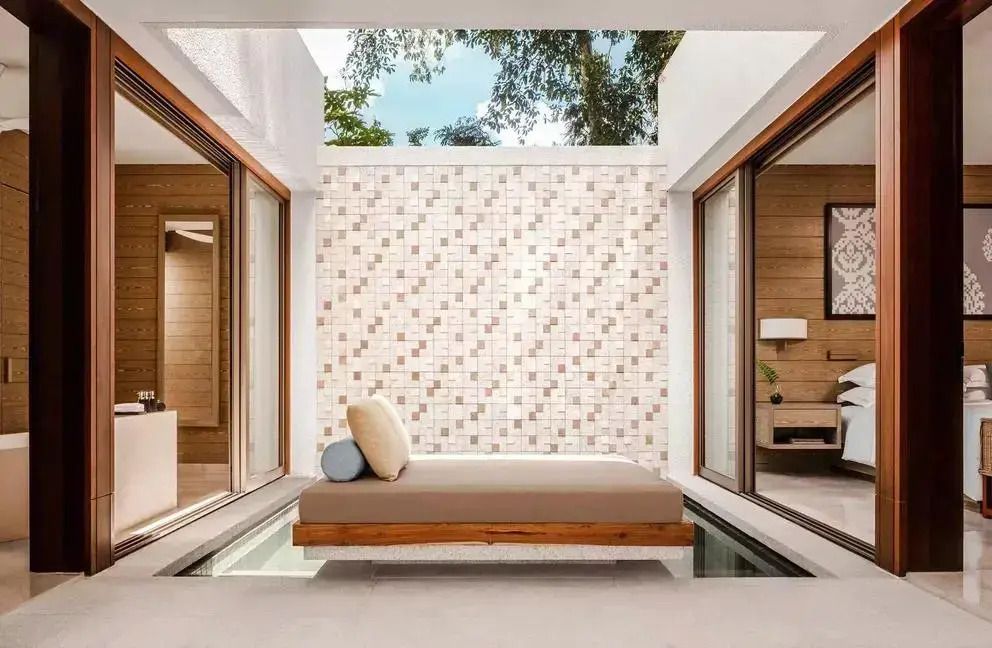 Lichtdurchflutete Suite mit modernem Bett und offenen Glaswänden mit Blick ins Freie
