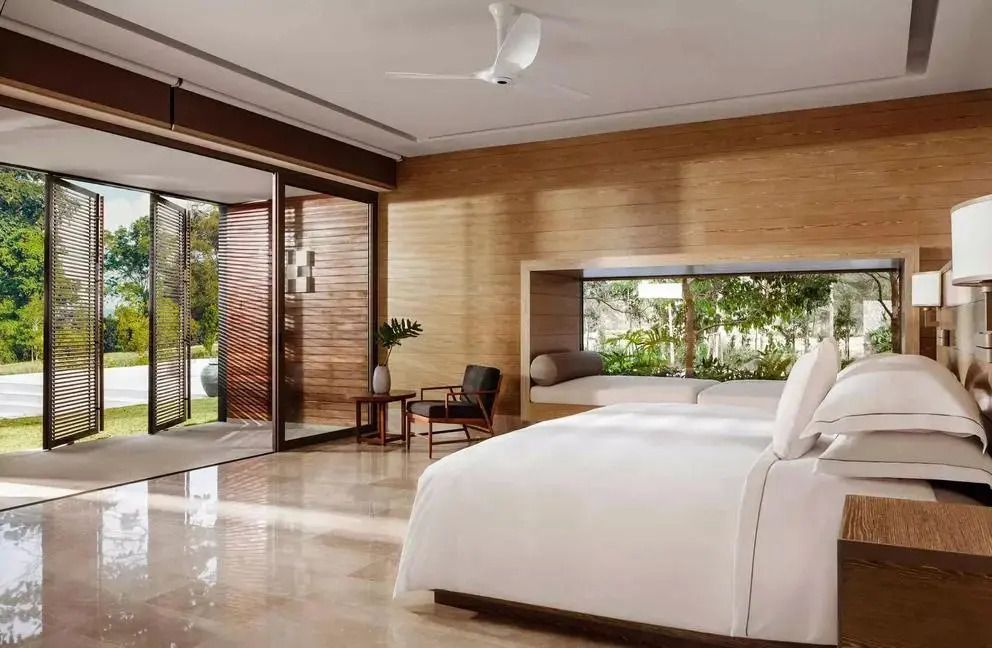 Luxuriöses Schlafzimmer mit großen Fenstern und Blick in den Garten