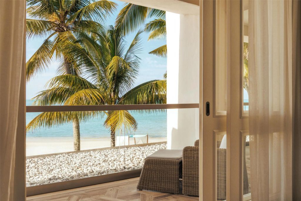 Strandblick von der Terrasse der Beach Front Suite mit Palmen im Vordergrund.