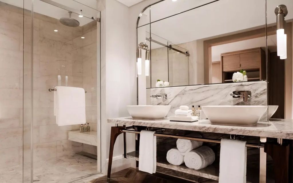 Elegantes Badezimmer mit Marmorwaschbecken, großer Spiegel und Dusche