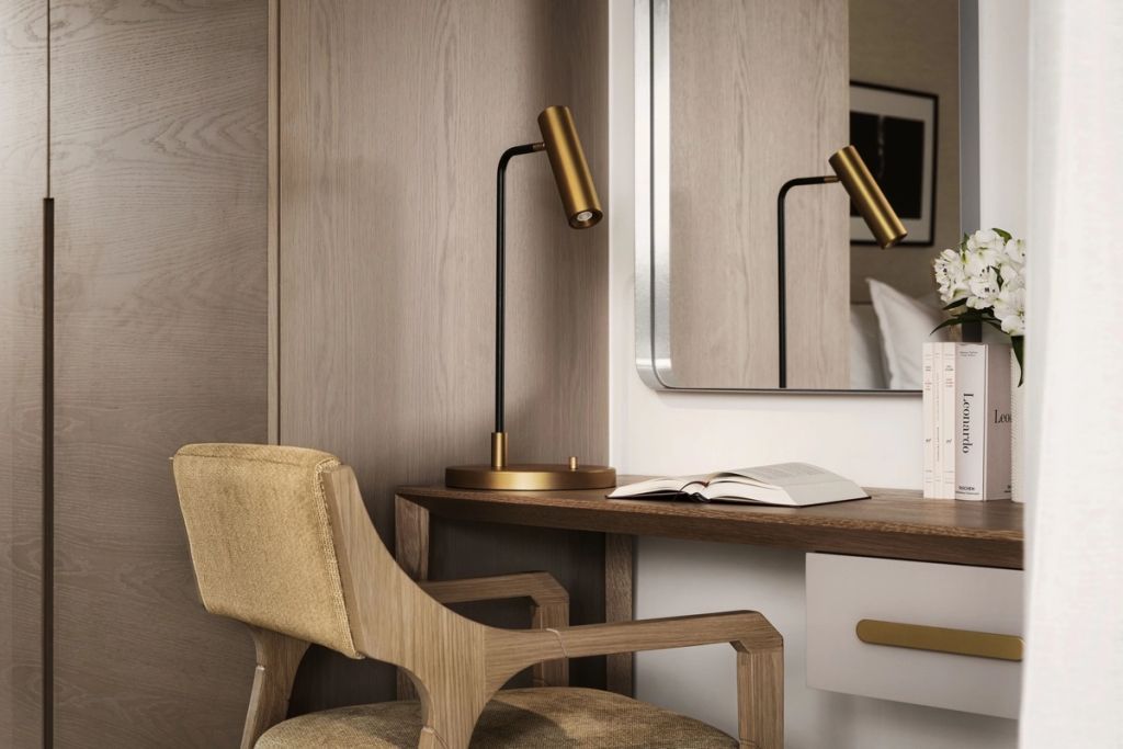 Arbeitsbereich mit modernem Holzstuhl und eleganter Tischlampe neben einem Spiegel.