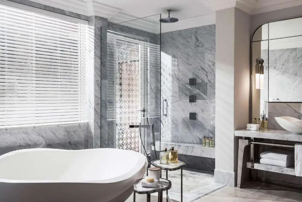 Luxuriöses Badezimmer mit freistehender Badewanne und Marmorwänden in Villa One