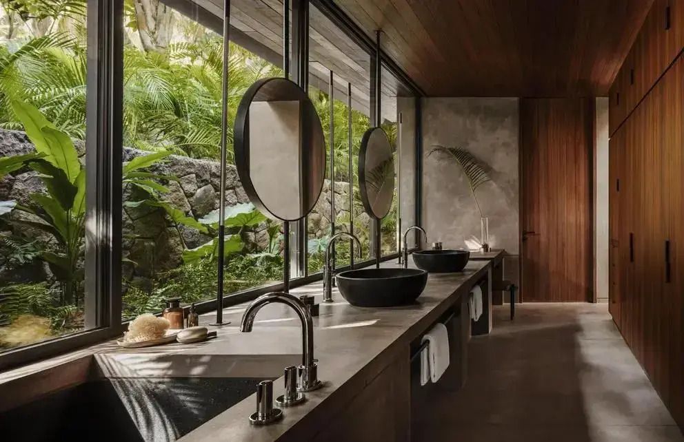 Modernes Badezimmer mit Naturstein Waschbecken und Blick auf tropische Vegetation