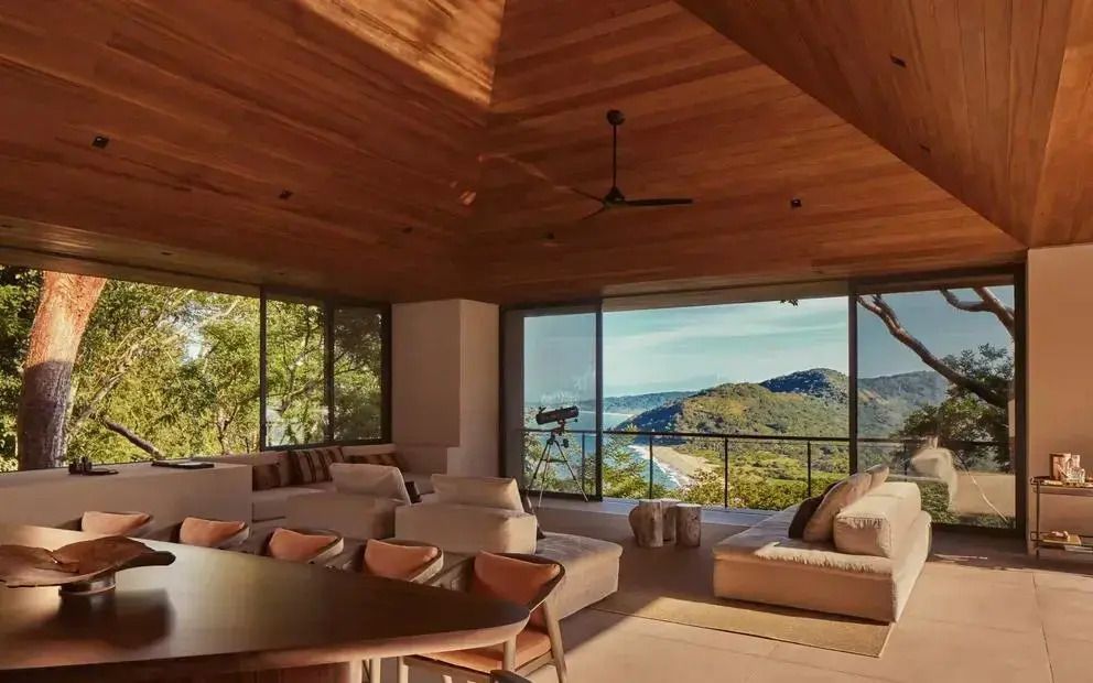 Luxuriöse Wohnzimmereinrichtung mit Panoramablick aufs Meer und bewaldete Hügel