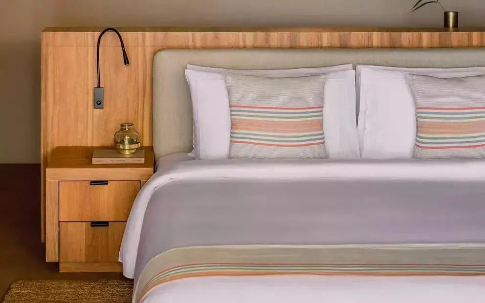 Elegantes Schlafzimmer mit Holzkopfteil und modernem Leselicht
