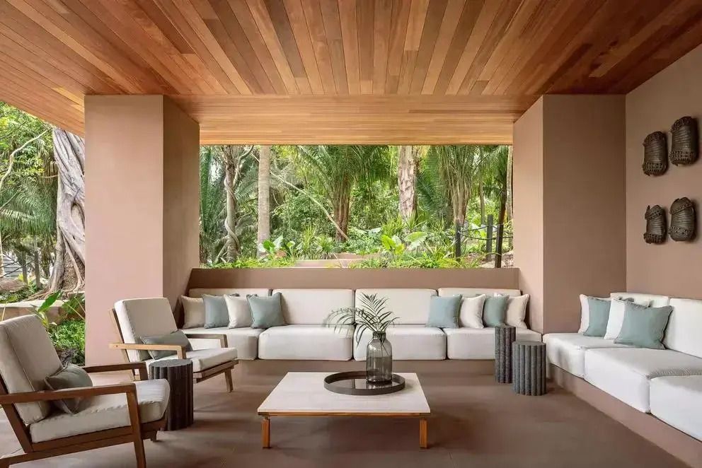 Offener Wohnbereich mit weißen Sofas und Blick auf tropische Vegetation