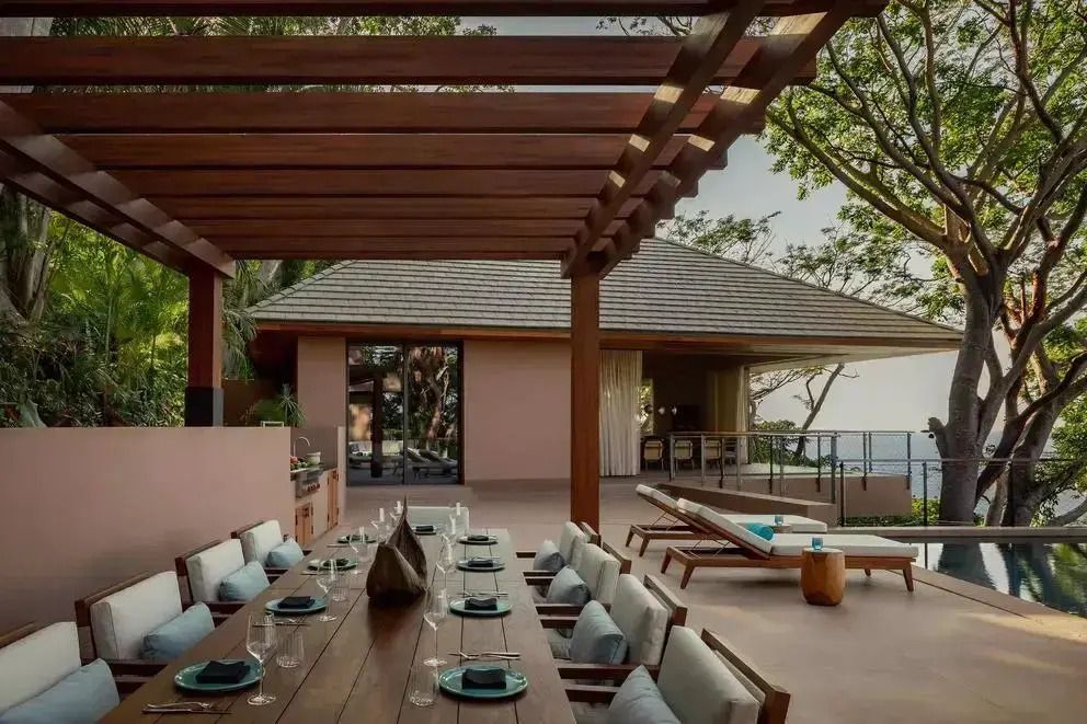 Terrasse mit Holzpergola, großem Esstisch und Meerblick