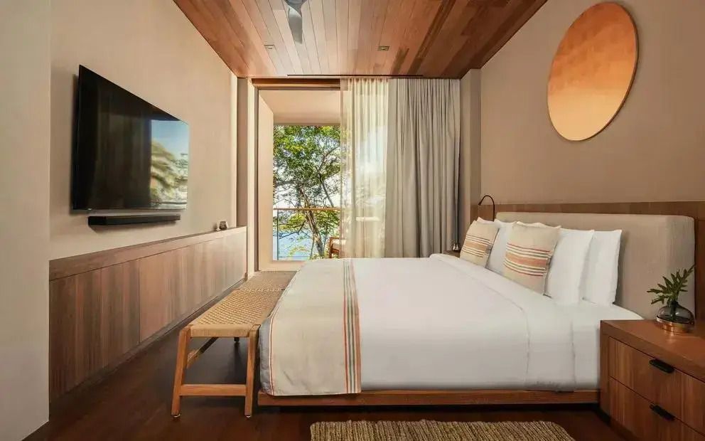 Zimmer mit großem Bett und Blick auf die Natur durch große Fenster