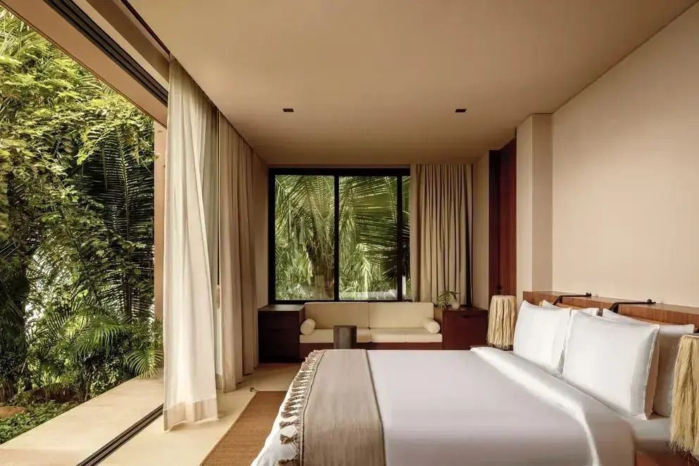 Elegantes Schlafzimmer mit großen Fenstern und üppigem Grünblick