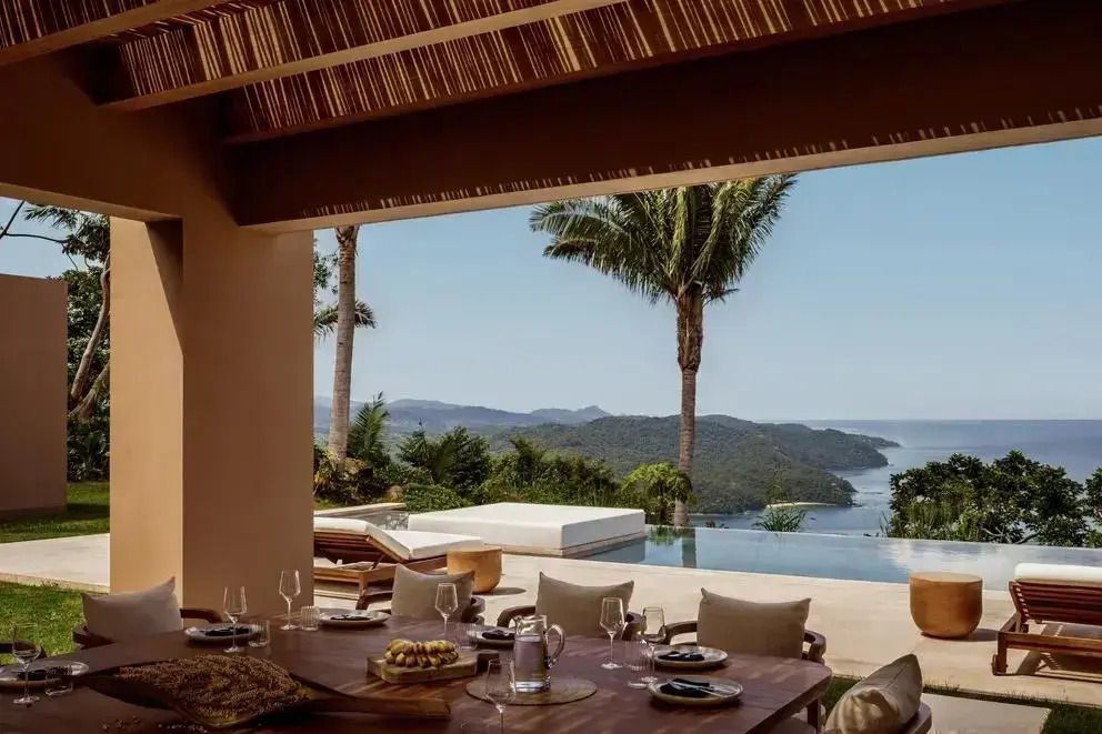 Terrasse mit Infinity-Pool und Blick auf den Ozean und die bewaldeten Hügel