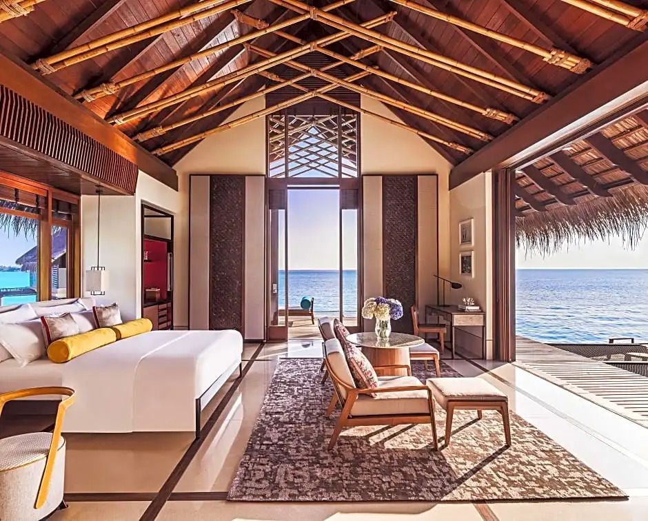 Innenansicht einer luxuriösen Wasser-Villa mit Doppelbett und Meerblick