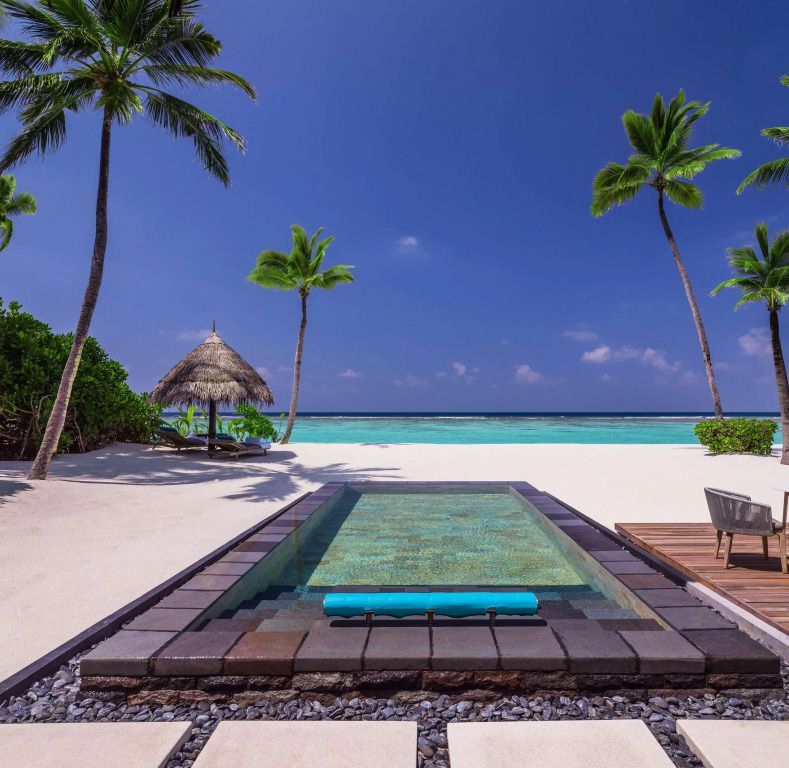 Privater Pool mit Blick auf weißen Sandstrand und Palmen