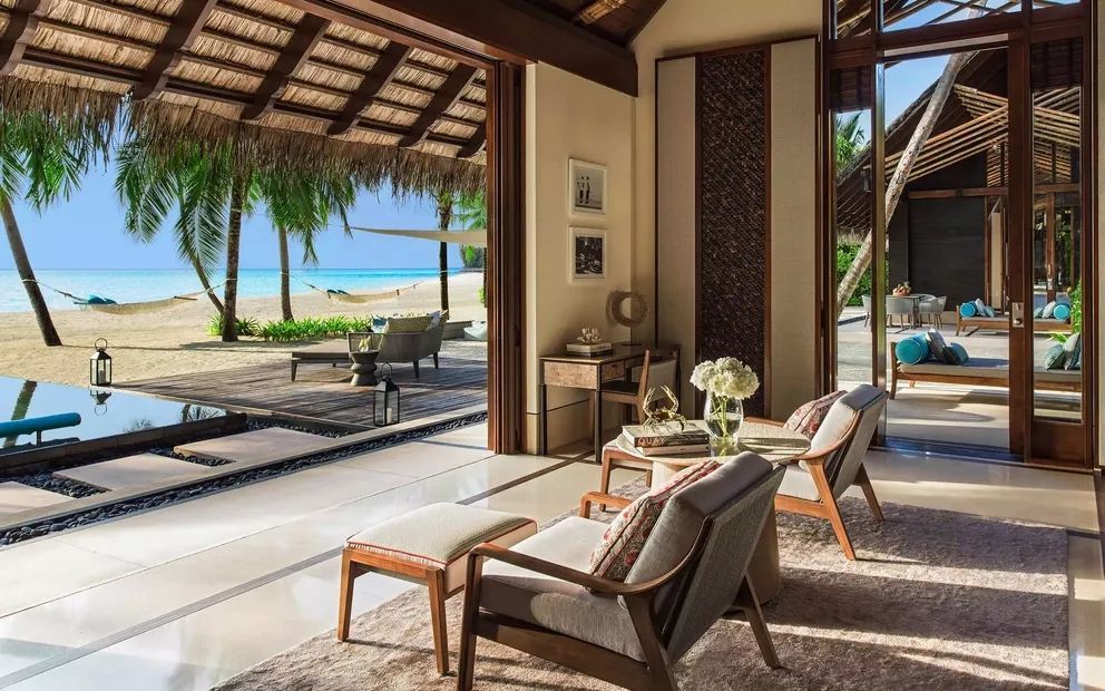 Elegantes Wohnzimmer mit Blick auf Meer und Strand, offene Türen, gemütliche Einrichtung