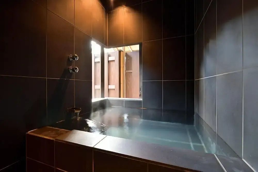 Elegantes Badezimmer mit tiefem, dunklem Keramikbad und natürlichem Licht