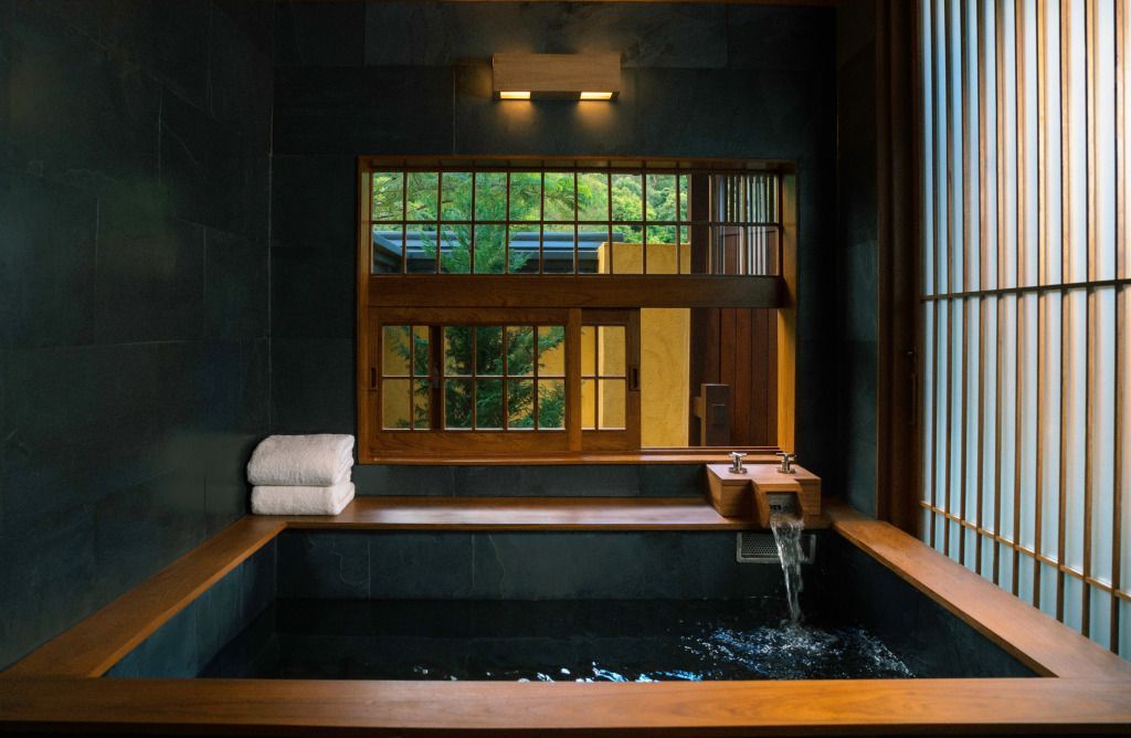 Japanischer Badebereich mit Holzverkleidung und fließendem Wasser im Onsen-Stil