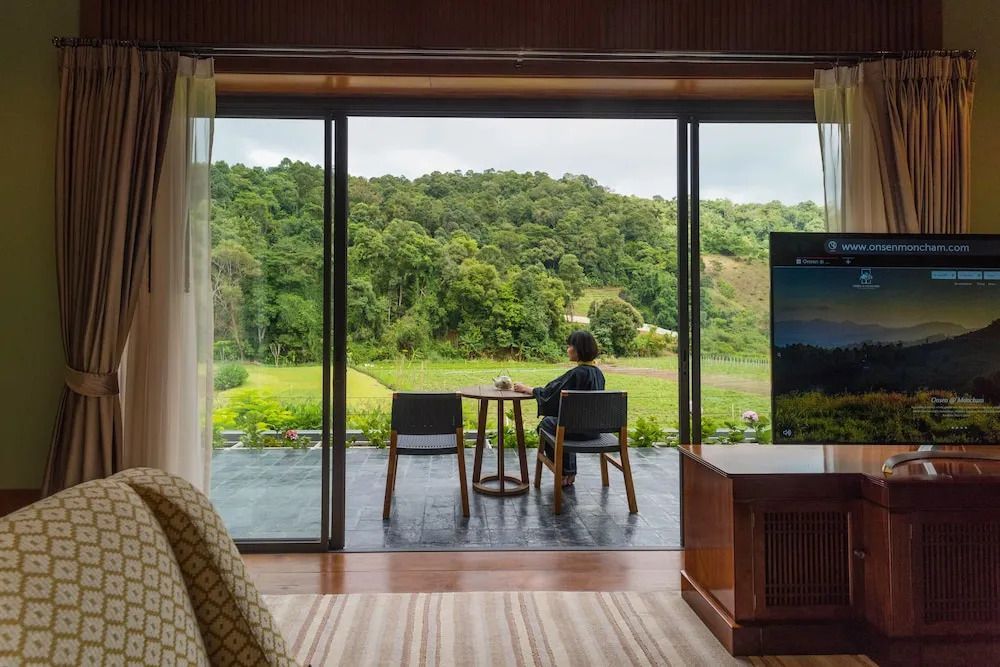 Blick vom Balkon der Suite auf üppige grüne Landschaft und Wald.