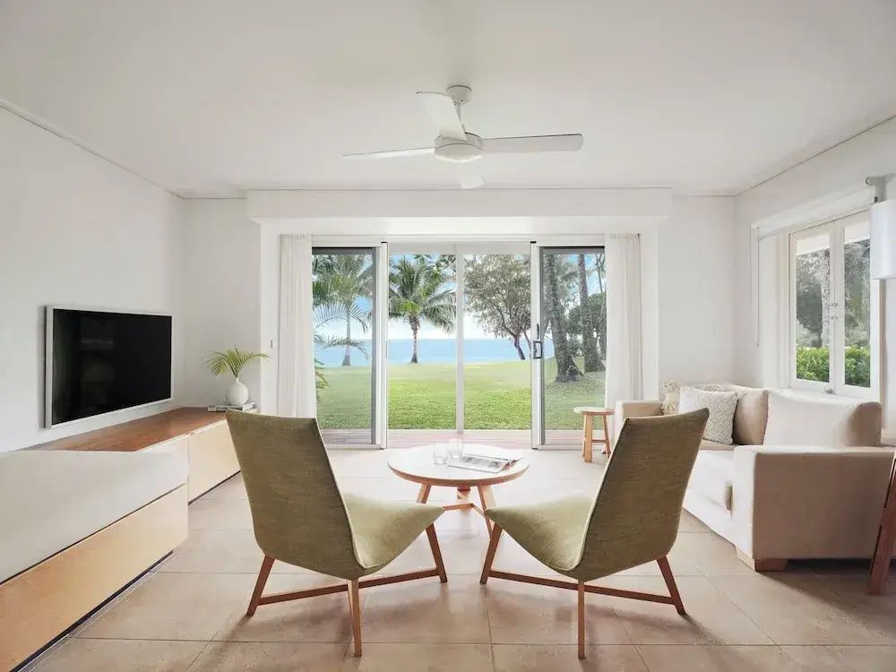 Geräumiger Wohnbereich einer Suite mit Blick auf Palmen und das Meer